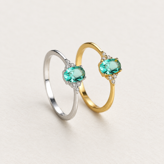 Anillo "Mística Verde" con Circonita Esmeralda Ovalada y Zirconias sobre fondo marfil con luz suave — Aurora Boré